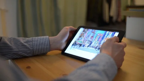 Browsing photo of Tokio in Google app - man using Tablet pc Home planning travel Stock Footage 100327977