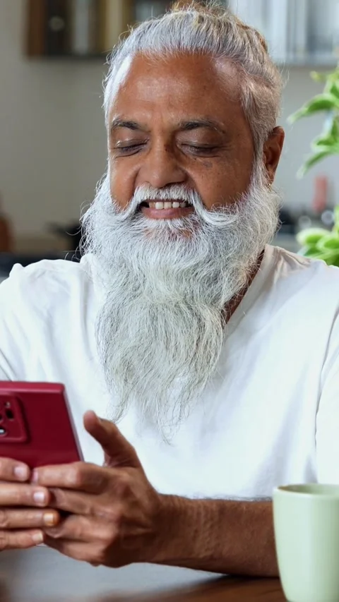 Browsing smartphone at breakfast, stylish Indian mid age man in modern kitchen Video stock 342756758