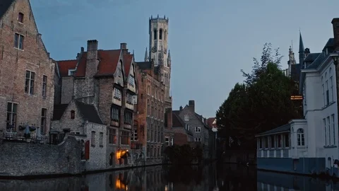 Bruges: twilight typical view of hotels at river and tower of Belfort Van Brugge Stock Footage 124395116