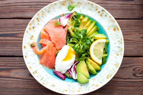 Brunch with poached egg, avocado, arugula, flax seeds and salted salmon on .. Stock Photos