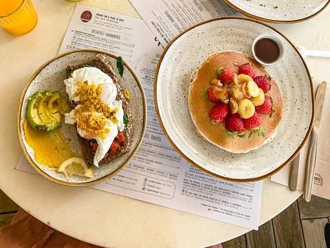 Brunch table with pancakes and avocado eggs Benedict toast Stock Photos