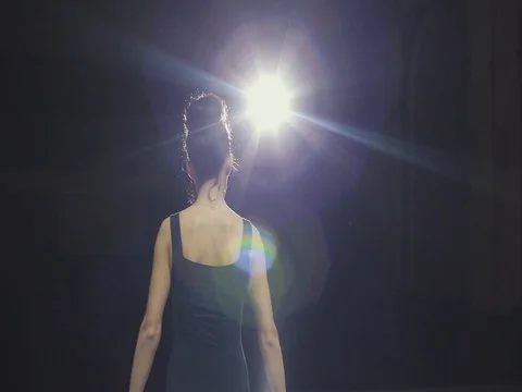 Brunette ballerina dancing on an empty stage in front of rays of light 2 Stock-Footage 80498444