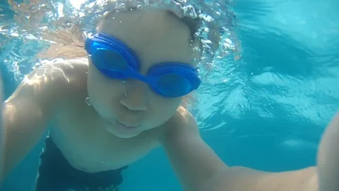 Brunette boy diving &amp; taking Selfie under the water in the swimming pool. An Video stock 111256531