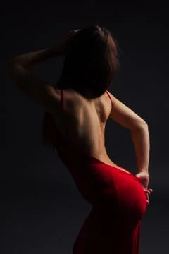 Brunette on a dark background posing in a red dress Stock Photos
