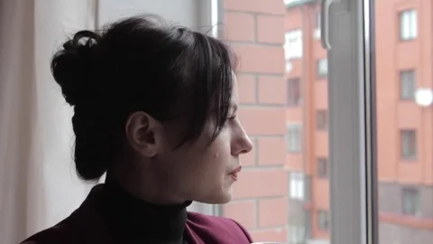 Brunette drinking coffee and looking out of the window Vídeo Stock 74659401