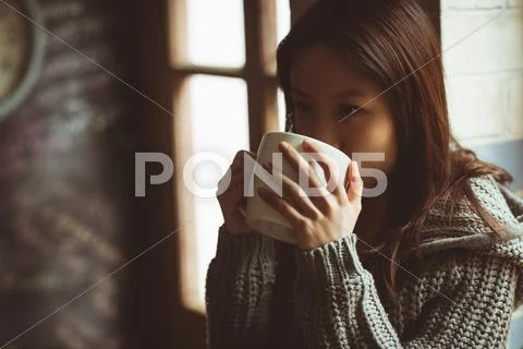 Brunette Drinking Tea Sitting On The Kitchen Counter At Home