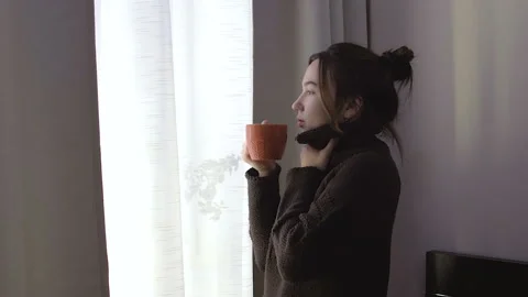 Brunette drinking tea by the window. Видео 102890666