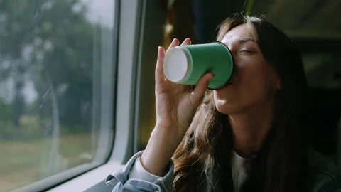 Brunette drinks coffee on the train in a good mood. The joy of traveling Stock Footage 242000144