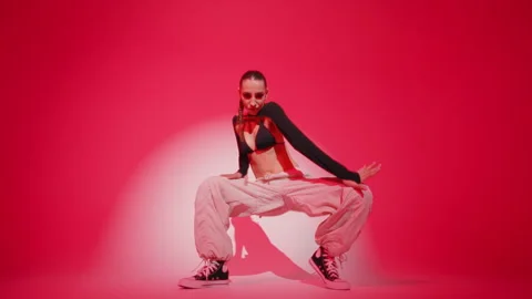 Brunette female dancing energetically performing hip hop dance on red background Stock Footage 277533759