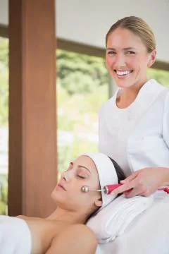 Brunette getting micro dermabrasion with therapist smiling at camera Stock Photos