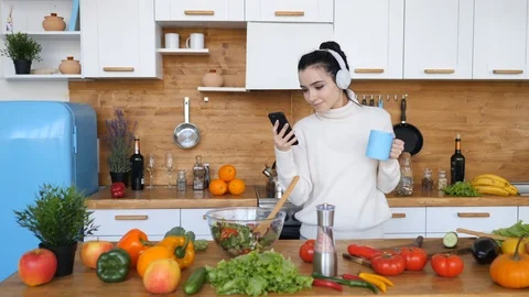 Brunette Girl Dancing And Using Smartphone In Kitchen With Cup In Hand. Stock Footage 105301243
