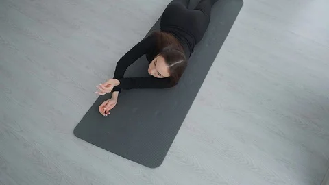 Brunette girl doing exercise, twisting on the yoga Mat during morning session. Stock Footage 128997706