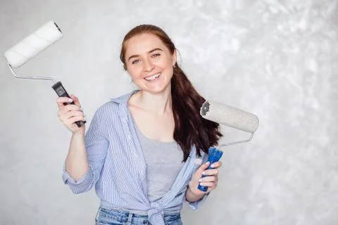 A brunette girl is resting while repairing a house. A young smiling beautiful Stock Photos