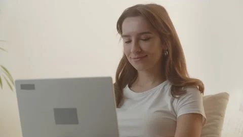 Brunette girl using a computer. A young woman is writing a study project using Stock Footage 234898442