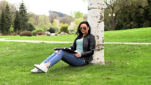 Brunette on the grass with a computer Vídeos de archivo 107072492