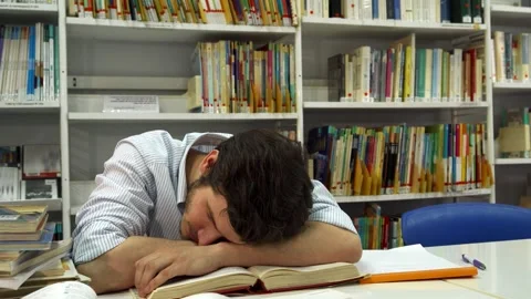 Brunette guy dozing off at the library table Stock Footage 311990119