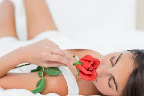Brunette lying on her back while smelling a rose Photos