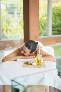 Brunette lying on massage table with tray of beauty treatments Stock Photos