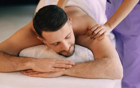 Brunette man relaxing in the spa while getting back massage. Fotos de archivo