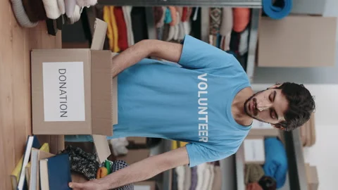 Brunette man standing at the warehouse while sorting and iterating clothes for Stock Footage 183993840