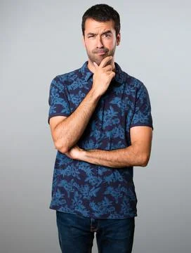 Brunette man thinking on grey background Stock Photos