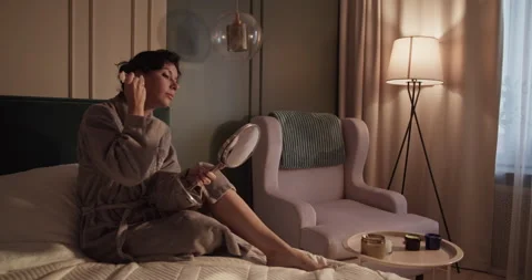 Brunette massaging face on bed Stock Footage 207669907