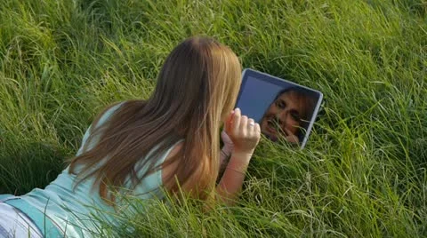 Brunette in meadow using a digital tablet Stock Footage 20587516