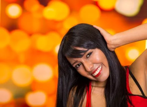 Brunette model posing happily in front of blurry lights background, touching Stock Photos