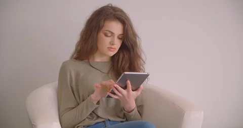 Brunette model working with tablet sitting in armchair being busy isolated on Video stock 112328088