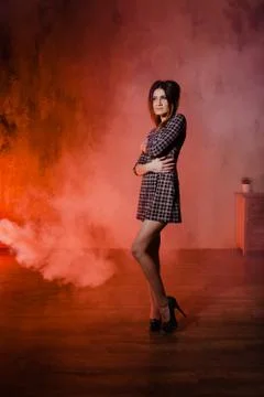 Brunette posing in a cloud of orange smoke Stock Photos