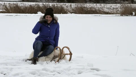 Brunette posing on a sled in the winter on the street near 動画素材 105680130