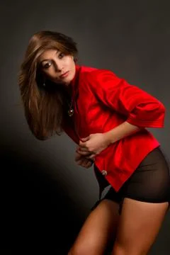 Brunette in a red jacket on a gray background Stock Photos