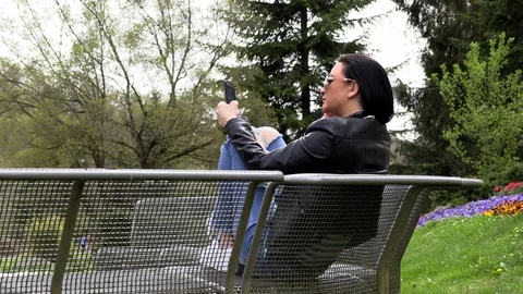 Brunette sits on a street bench and listens to music Stock Footage 106952024