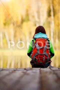Brunette Sitting Back With Backpack On Bridge Near Water