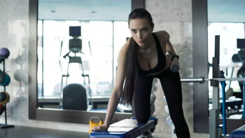 Brunette with slender physique working out exercises using dumbbells. One real p Stock Footage 199490760