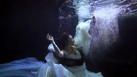 The brunette soars in dark water with bubbles in flowing light canvases and Vidéo 195528797
