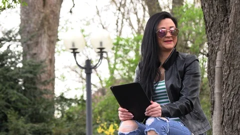 Brunette on a street bench with a tablet 库存影片 106897250