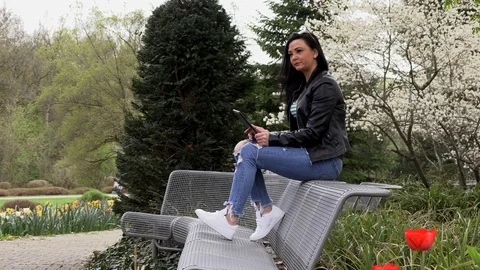 Brunette on a street bench with a tablet 库存影片 106897354