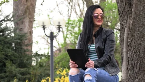 Brunette on a street bench with a tablet Stock Footage 106915837