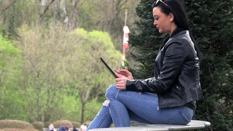 Brunette on a street bench with a tablet Stock Footage 106915903