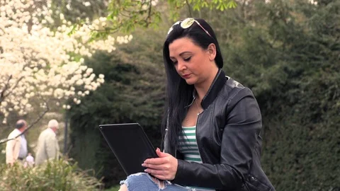 Brunette on a street bench with a tablet Stock Footage 106916260