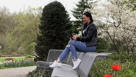 Brunette on a street bench with a tablet Stock Footage 106930684