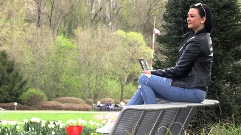 Brunette on a street bench with a tablet Stockbeeldmateriaal 106951567