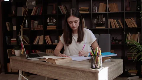 Brunette studying and preparing homework in university library full of Stock Footage 304957978
