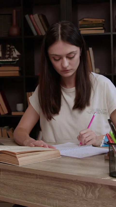 Brunette studying and preparing homework in university library full of Stock Footage 305408839