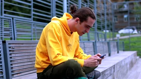 Brunette stylish man using smart phone for gaming online on sport area. Excited Stockbeeldmateriaal 135667216