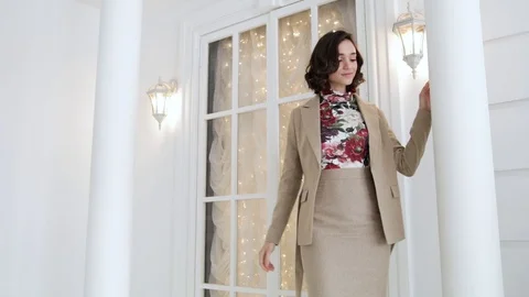 Brunette takes off her jacket posing in a beige suit next to the columns   Stock Footage 102050181