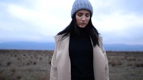 Brunette in unbuttoned spring coat on field slow motion Stock Footage 105294293