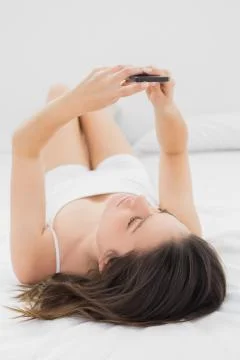 Brunette using mobile phone in bed Stock Photos