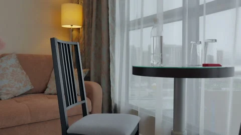 A brunette in a white robe sits at a table and drinks water at the hotel Stock Footage 87907692